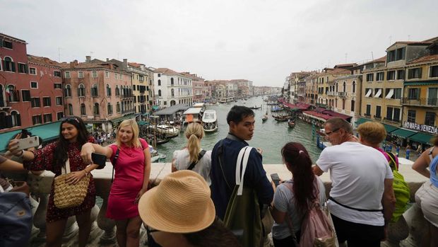 Tourists visit Rialto bridge, in Venice, Italy, Wednesday, Sept. 13, 2023. The Italian city of Venice has been struggling to manage an onslaught of tourists in the budget travel era. The stakes for the fragile lagoon city are high this week as a UNESCO committee decides whether to insert Venice on its list of endangered sites. (AP Photo/Luca Bruno)