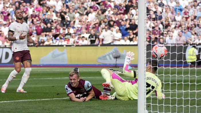 West Hams James Ward-Prowse, on the ground, scores the opening goal during the English Premier League soccer match between West Ham United and Manchester City at London stadium in London, Saturday, Sept. 16, 2023. (AP Photo/Kin Cheung)
