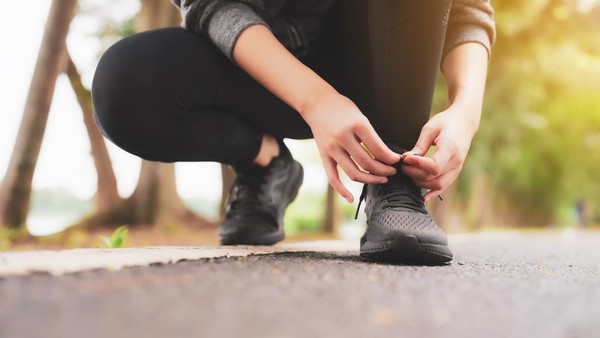 Closeup of woman tying shoe laces. Asian female sport fitness runner getting ready for jogging outdoors in public park