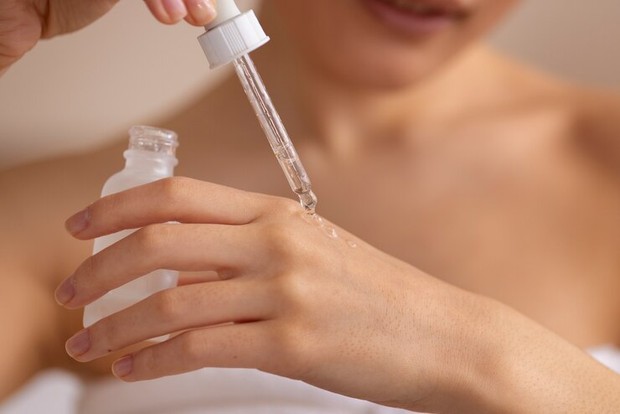 Foto perempuan menggunakan serum tubuh