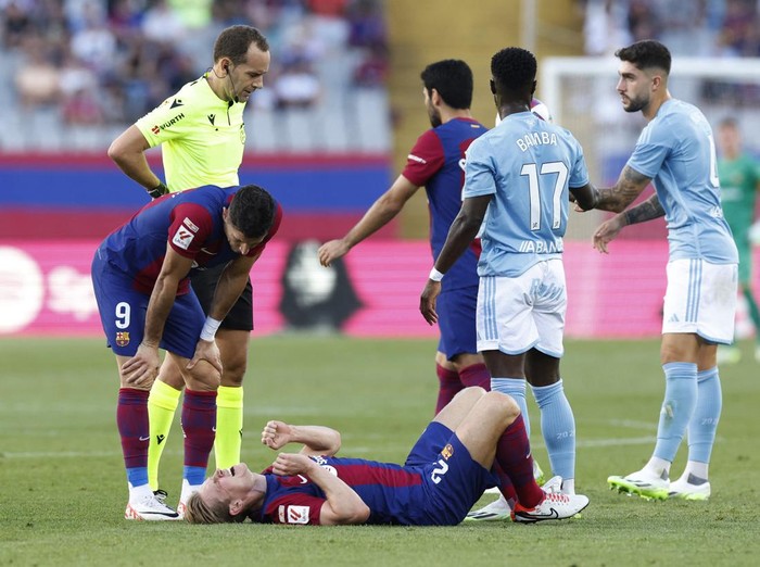 Soccer Football - LaLiga - FC Barcelona v Celta Vigo - Estadi Olimpic Lluis Companys, Barcelona, Spain - September 23, 2023 FC Barcelona's Frenkie de Jong reacts after sustaining an injury as Robert Lewandowski and referee Mario Melero Lopez look on REUTERS/Albert Gea