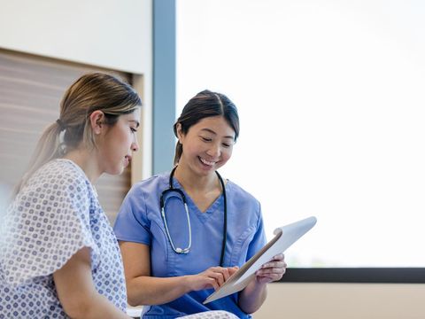 At the hospital, the mid adult female doctor gives her young adult female patient the good news from her medical tests.