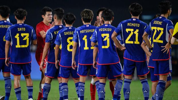 Japan's players (blue) speak with Hong Kong's players (red) after the men's semi-final football match between Hong Kong and Japan during the 2022 Asian Games in Hangzhou in China's eastern Zhejiang province on October 4, 2023. (Photo by Philip FONG / AFP)