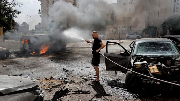 A man works to put out a fire engulfing a van, as rockets are launched from the Gaza Strip, in Ashkelon, southern Israel October 7, 2023. REUTERS/Ammar Awad