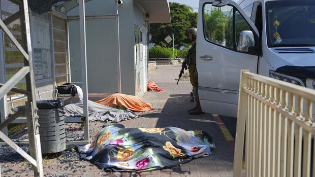 An Israeli soldier stands by the bodies of Israelis killed by Palestinian armed militants who entered from the Gaza Strip, in the southern Israeli city of Sderot, Saturday, Oct. 7, 2023. Hamas, the militant group ruling the Gaza Strip, carried out a surprise, multi-front attack on Israel at daybreak Saturday, firing thousands of rockets and infiltrating the country by land, air and sea. (AP Photo/Tsafrir Abayov)