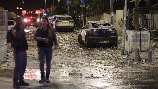 Israeli security forces stand along a debris-strewn street in Tel Aviv, after it was hit by a rocket fired by Palestinian militants from the Gaza Strip on October 7, 2023. Palestinian militant group Hamas launched a surprise large-scale attack against Israel on October 7, firing thousands of rockets from Gaza and sending fighters to kill or abduct people as Israel retaliated with devastating air strikes. (Photo by JACK GUEZ / AFP)