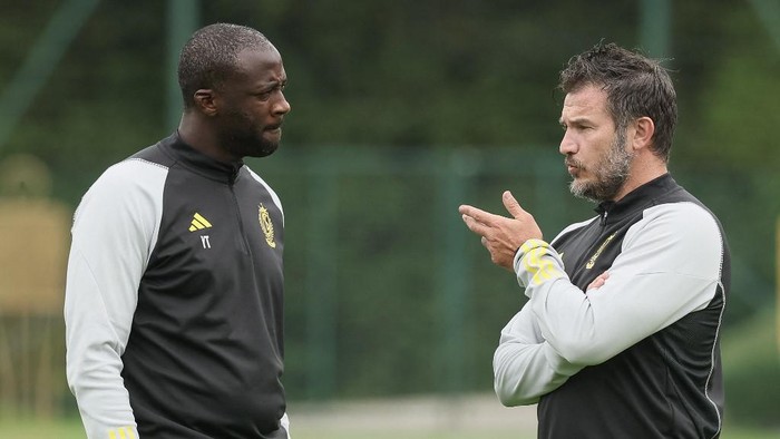 Standard Lieges head coach Carl Hoefkens (R) and assistant coach Yaya Toure speak during a training session of the Belgian first division football team at Angleur on the outskirts of Liege on June 29, 2023, ahead of the forthcoming 2023-2024 season. (Photo by BRUNO FAHY / Belga / AFP) / Belgium OUT