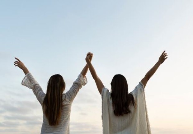 Dua perempuan sedang mengangkat tangannya