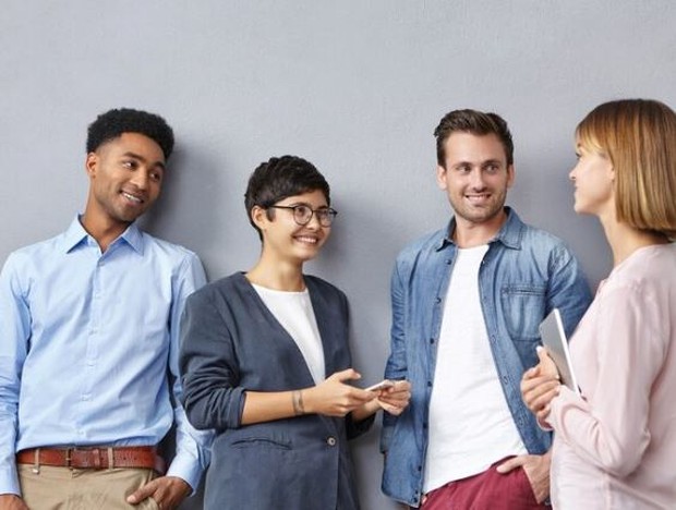 Wajah ramah, tone lembut/ foto: Freepik/ wayhomestudio Empat orang sedang mengobrol sambil berdiri