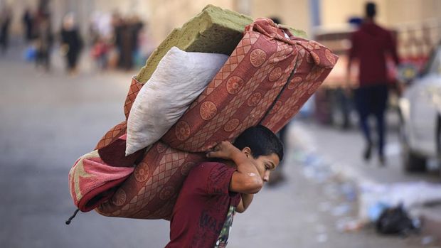 A boy carries a mattres as Palestinians with their belongings flee to safer areas in Gaza City after Israeli air strikes, on October 13, 2023. Israel has called for the immediate relocation of 1.1 million people in Gaza amid its massive bombardment in retaliation for Hamas's attacks, with the United Nations warning of 