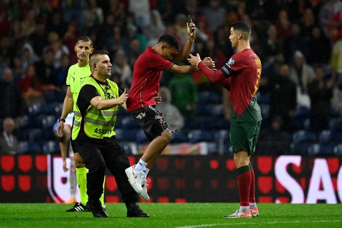Soccer Football - Euro 2024 Qualifier - Group J - Portugal v Slovakia - Estadio do Dragao, Porto, Portugal - October 13, 2023
Young pitch invader takes a selfie with Portugal's Cristiano Ronaldo during the match before being detained by a steward REUTERS/Pedro Nunes