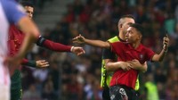 Tentu saja pada akhirnya si penyusup lapangan harus rela digelandang pergi, walaupun tampaknya ia berat melepas kebersamaan dengan Ronaldo. Foto: REUTERS/PEDRO NUNES