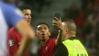 Si penyusup lapangan bersikeras selfie dengan CR7 walaupun sudah dipegangi steward. Foto: REUTERS/PEDRO NUNES
