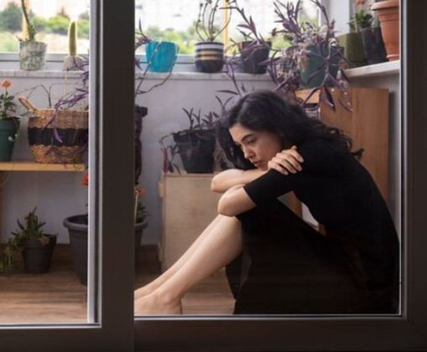 Perempuan berbaju hitam sedang duduk di balkon