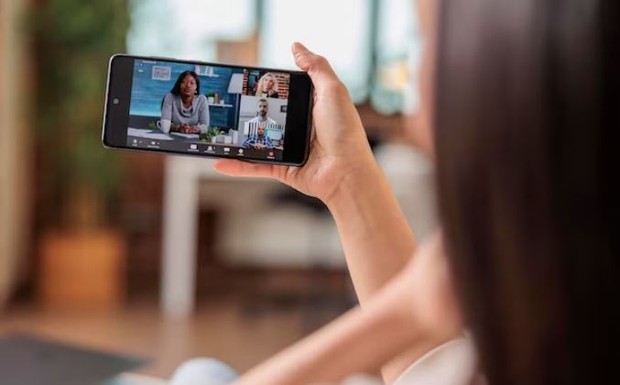 Seorang perempuan sedang menonton video di handphone