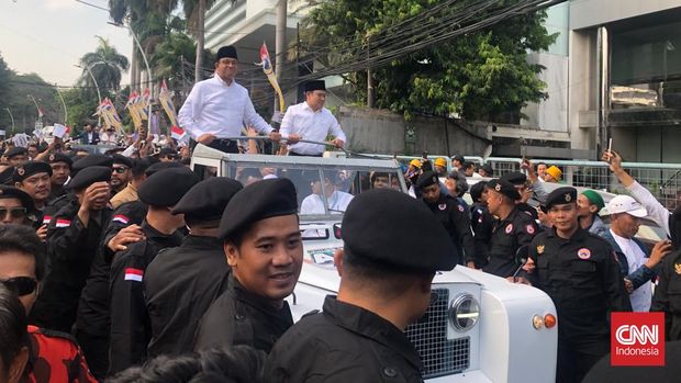 Pasangan bakal capres-cawapres Koalisi Perubahan Anies Baswedan-Muhaimin Iskandar atau Cak Imin (AMIN) memulai arak-arakan mendaftar ke KPU dengan menaiki mobil jip berwarna putih bergambar kedua paslon dengan model atap terbuka. CNN Indonesia/Ramadhan Rizki
