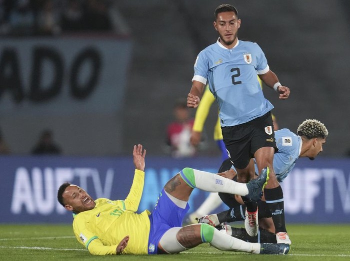 Brazil's Neymar falls while fighting for a ball with Uruguay's Sebastian Caceres during a qualifying soccer match for the FIFA World Cup 2026 at Centenario stadium in Montevideo, Uruguay, Tuesday, Oct. 17, 2023. (AP Photo/Matilde Campodonico)