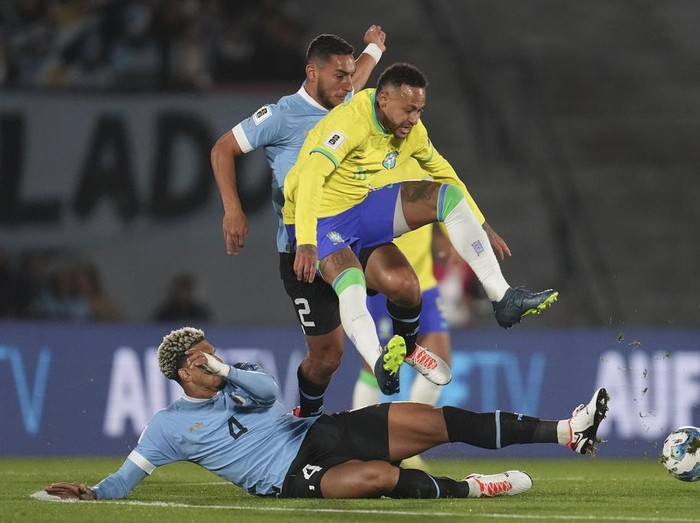 Brazil's Neymar is tackled by Uruguay's Ronald Araujo, on the ground, during a qualifying soccer match for the FIFA World Cup 2026 at Centenario stadium in Montevideo, Uruguay, Tuesday, Oct. 17, 2023. (AP Photo/Matilde Campodonico)