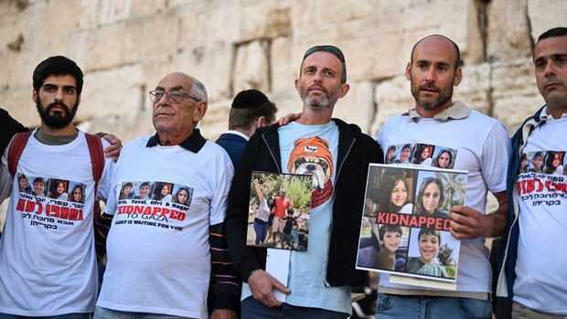Relatives of missing Israelis lift portraits of their loved ones in front of the Western Wall while attending a day of prayer in the Old City of Jerusalem on October 19, 2023, for the safe return of hostages taken by Palestinian fighters after they breached the fortified Gaza border with Israel on October 7. There are fears of worse to come if Israel launches an anticipated ground invasion to destroy Hamas and rescue Israeli and foreign hostages, whose known number Israel on October 19 revised up to 203. (Photo by Yuri CORTEZ / AFP) (Photo by YURI CORTEZ/AFP via Getty Images)