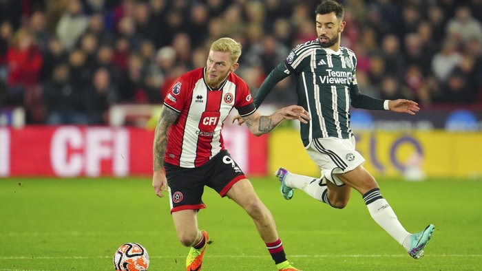 Sheffield Uniteds Oli McBurnie, left, challenges for the ball with Manchester Uniteds Bruno Fernandes during the English Premier League soccer match between Sheffield United and Manchester United at Bramall Lane in Sheffield, England, Saturday, Oct. 21, 2023. (AP Photo/Jon Super)