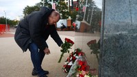 Di luar Old Trafford, seorang suporter meletakkan bunga di depan tugu patung Sir Bobby Charlton. Foto: REUTERS/CARL RECINE