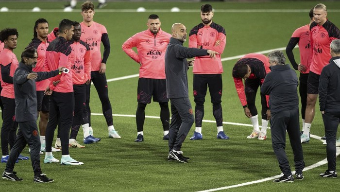 Manchester Citys head coach Josep Guardiola, center, talks to his team during a training session at the Wankdorf stadium in Bern, Switzerland, Tuesday, Oct. 24, 2023. BSC Young Boys will play Manchester City in the Champions League group stage match on Wednesday. (Peter Schneider/Keystone via AP)