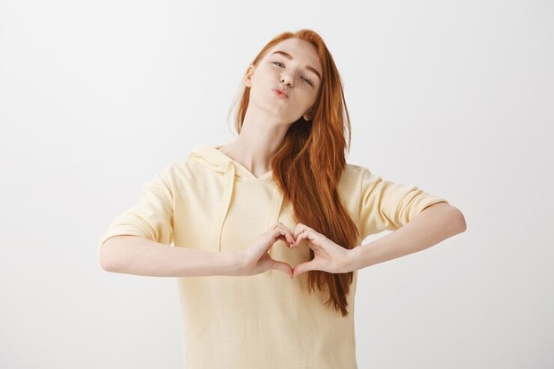 Foto seorang perempuan membuat simbol tangan love