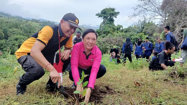 Ps Kasat Binmas Polres Jayapura Ipda Made Ambo dan istri, Reynie Wori mennam pohon.