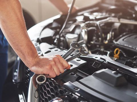 Picture showing muscular car service worker repairing vehicle.