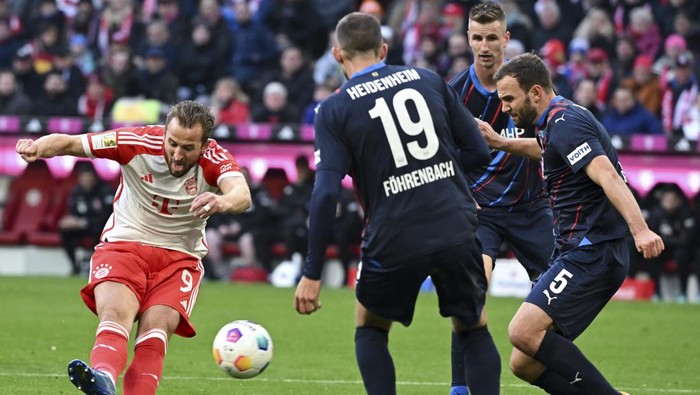 Bayerns Harry Kane, left, scores his sides opening goal during the German Bundesliga soccer match between Bayern Munich and Heidenheim at the Allianz Arena stadium in Munich, Germany, Saturday, Nov. 11, 2023. (Sven Hoppe/dpa via AP)