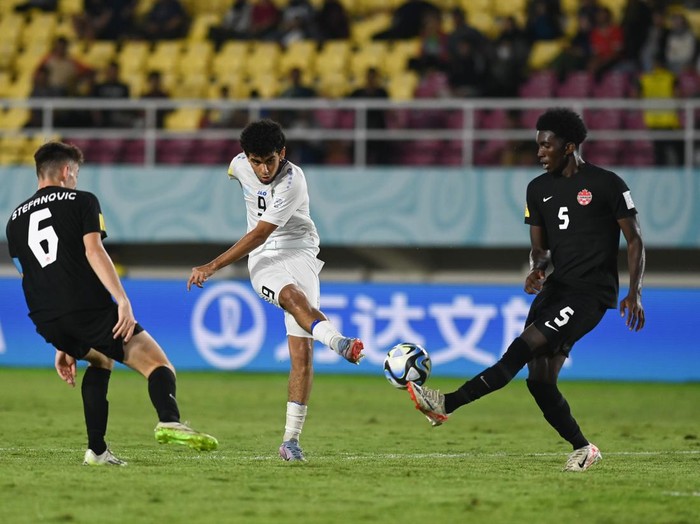 Pesepak bola Timnas Uzbekistan Amirbek Saidov (tengah) melepaskan tendangan dengan dihadang pesepak bola Timnas Kanada Chimere Omeze (kanan) dan Lazar Stefanovic (kiri) pada pertandingan lanjutan Grup B Piala Dunia U-17 2023 di Stadion Manahan, Solo, Jawa Tengah, Senin (13/11/2023). Timnas Uzbekistan mengalahkan Timnas Kanada dengan skor 3-0. ANTARA FOTO/Mohammad Ayudha/aww.