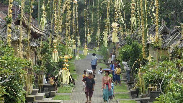 Warga berjalan di antara rumah-rumah tradisional berhiaskan penjor di Desa Adat Penglipuran, Bangli, Bali. (ANTARA FOTO/Ismar Patrizki)