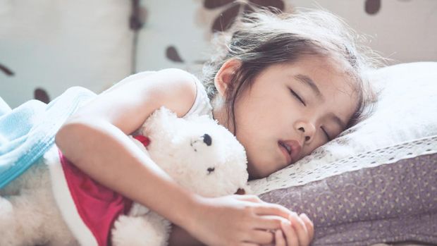Cute asian child girl sleeping and hugging her teddy bear in the bed