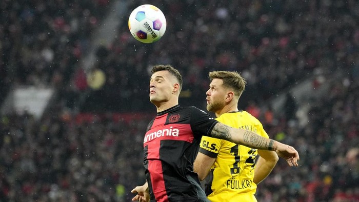 Leverkusens Granit Xhaka, left, and Dortmunds Niclas Fuellkrug challenge for the ball during the German Bundesliga soccer match between Bayer Leverkusen and Borussia Dortmund at the BayArena in Leverkusen, Germany, Sunday, Dec. 3, 2023 (AP Photo/Martin Meissner)