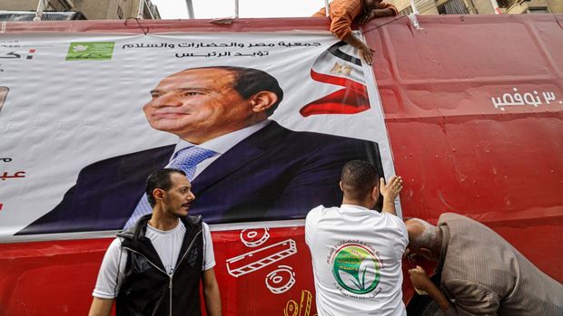 Pemilu Mesir 2023 Supporters hang a campaign banner of Egypt's President Abdel Fattah al-Sisi at a bus on a street in Cairo on December 7, 2023, ahead of the country's presidential election. Egyptian citizens living abroad will cast early ballots on December 8 in a presidential election, in a vote all but certain to give incumbent Sisi a third term in office. (Photo by Khaled DESOUKI / AFP)