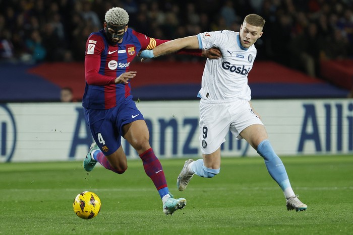 Barcelona's Ronald Araujo, left, and Girona's Artem Dovbyk challenge for the ball during the Spanish La Liga soccer match between Barcelona and Girona at the Olimpic Lluis Companys stadium in Barcelona, Spain, Sunday, Dec. 10, 2023. (AP Photo/Joan Monfort)