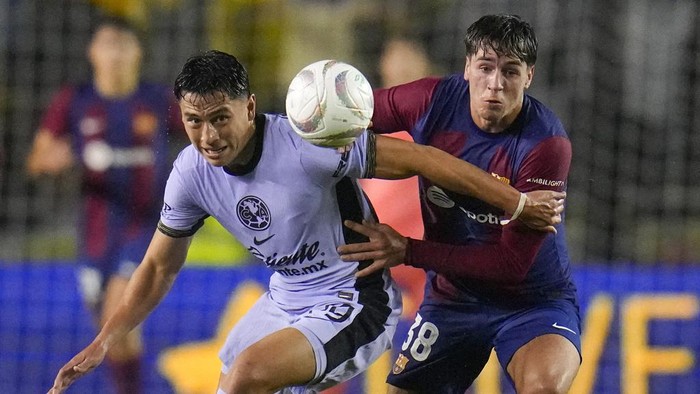 Club Americas Ramón Juárez, left, and Barcelonas Marc Guiu compete for the ball during the first half of a club friendly soccer match, Thursday, Dec. 21, 2023, at the Cotton Bowl in Dallas. (AP Photo/Julio Cortez)