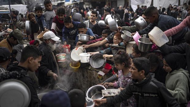 Palestinians converge for a free meal in Rafah, Gaza Strip, Thursday, Dec. 21, 2023. International aid agencies say Gaza is suffering from shortages of food, medicine and other basic supplies as a result of the two and a half month war between Israel and Hamas. (AP Photo/Fatima Shbair)