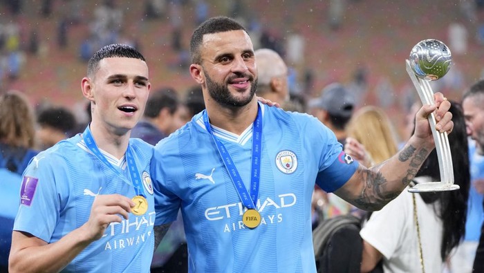 Manchester Citys Kyle Walker holds his silver ball award while posing with teammate Phil Foden, left, at the trophy after the end of the Soccer Club World Cup final match between Manchester City FC and Fluminense FC at King Abdullah Sports City Stadium in Jeddah, Saudi Arabia, Friday, Dec. 22, 2023. Manchester City won 4-0. (AP Photo/Manu Fernandez)
