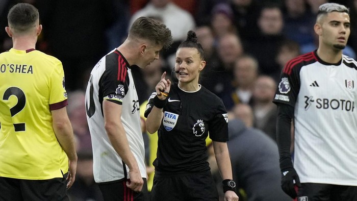 Referee Rebecca Welch holds a yellow card and speaks to Fulhams team captain Tom Cairney, before showing the card to Fulhams Calvin Bassey, during the English Premier League soccer match between Fulham and Burnley at Craven Cottage stadium in London, Saturday, Dec. 23, 2023. Welch is the first female referee ever to officiate an English Premier League game. (AP Photo/Alastair Grant)