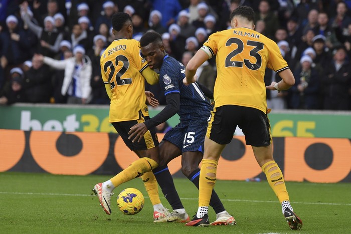 Chelseas Nicolas Jackson, centre, challenges for the ball with Wolverhampton Wanderers Nelson Semedo, left, and Wolverhampton Wanderers Max Kilman, right, during the English Premier League soccer match between Wolverhampton Wanderers and Chelsea at Molineux stadium in Wolverhampton, England, Sunday, Dec. 24, 2023. (AP Photo/Rui Vieira)