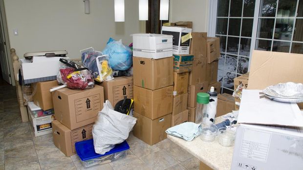 Messy dining room of a house after just moving in. There are moving boxes everywhere.