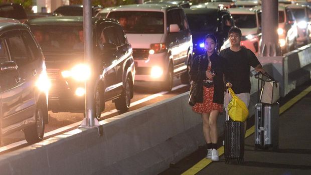 Calon penumpang pesawat berjalan di Jalan Tol Bali Mandara setelah mobil yang ditumpanginya terjebak kemacetan saat akan menuju ke Bandara Internasional I Gusti Ngurah Rai di Badung, Bali, Jumat (29/12/2023). Kemacetan itu terjadi sejak Jumat sore akibat padatnya kendaraan yang melintas di kawasan jalan akses Bandara I Gusti Ngurah Rai pada musim liburan akhir tahun. ANTARA FOTO/Fikri Yusuf/nym.