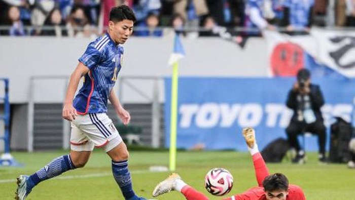 Thailands Jaroensak Wonggorn (R) falls on the pitch after a challenge from Japans Mao Hosoya (L) during the New Years Day international football friendly match between Japan and Thailand at the National Stadium in Tokyo on January 1, 2024. (Photo by Richard A. Brooks / AFP)