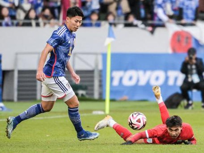 Thailands Jaroensak Wonggorn (R) falls on the pitch after a challenge from Japans Mao Hosoya (L) during the New Years Day international football friendly match between Japan and Thailand at the National Stadium in Tokyo on January 1, 2024. (Photo by Richard A. Brooks / AFP)