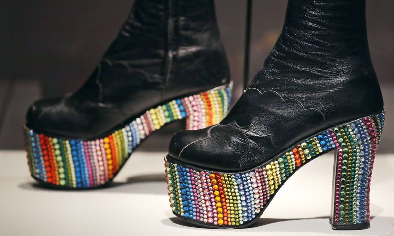 In this Tuesday, Nov.  15, 2016 photo, Elton John's rainbow glass embossed platform boots, designed by Bill Whitten in the 1970's, are displayed at the Peabody Essex Museum in Salem, Mass.  From flats to stilettos, what we put on our feet says something about who we are.  That's the premise of new exhibition in Massachusetts. 