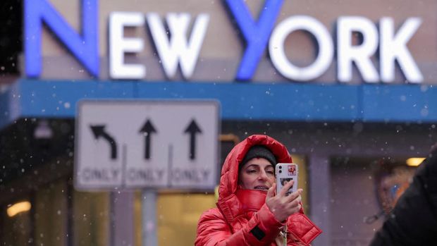A person holds a mobile as snow falls in Times Square in Manhattan, New York City, U.S., January 6, 2024. REUTERS/Andrew Kelly