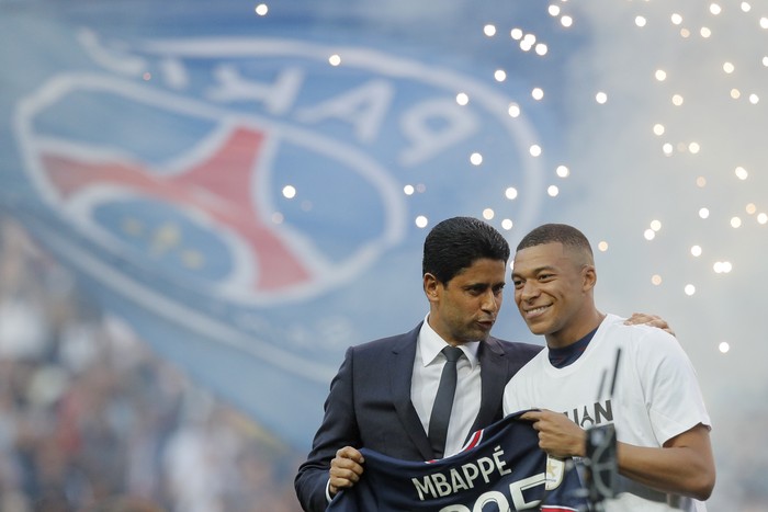 PSG President Nasser Al-Khelaifi, left, speaks to PSGs Kylian Mbappe who holds a shirt with his name and 2025 on it as it is announced he has signed a three year extension to his contract on the pitch ahead of the French League One soccer match between Paris Saint Germain and Metz at the Parc des Princes stadium in Paris, France, Saturday, May 21, 2022. (AP Photo/Michel Spingler)
