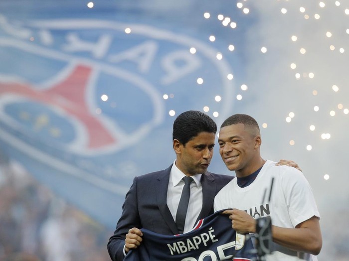 PSG President Nasser Al-Khelaifi, left, speaks to PSG's Kylian Mbappe who holds a shirt with his name and 2025 on it as it is announced he has signed a three year extension to his contract on the pitch ahead of the French League One soccer match between Paris Saint Germain and Metz at the Parc des Princes stadium in Paris, France, Saturday, May 21, 2022. (AP Photo/Michel Spingler)
