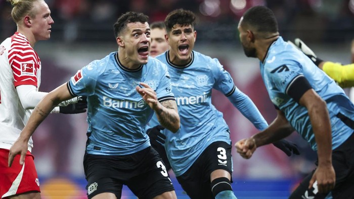 Leverkusens Jonathan Tah right, celebrates with teammates Piero Hincapie, centre and Granit Xhaka after his goal to make it 2-2. during the Bundesliga soccer match between RB Leipzig and Bayer Leverkusen at Red Bull Arena., Leipzig, Germany, Saturday Jan. 20, 2024. (Jan Woitas/dpa via AP)
